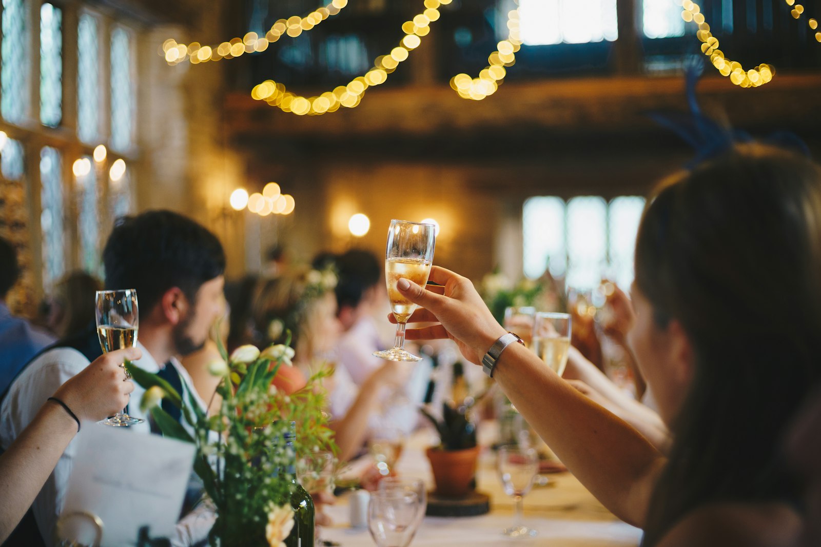 Guests raising champagne glasses in a toast at a warmly lit fundraising dinner event